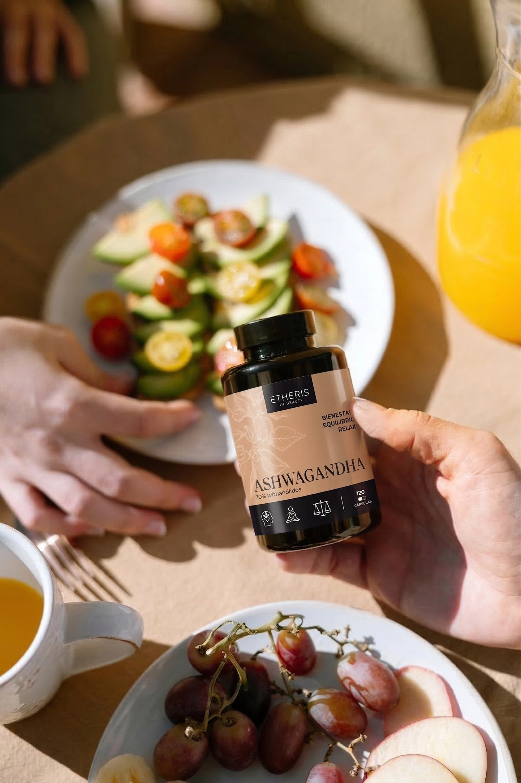 Persona sosteniendo Ashwagandha Etheris durante un desayuno saludable con fruta fresca